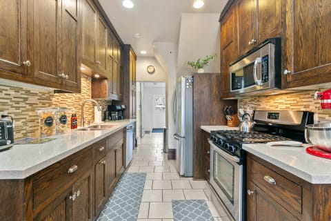 A modern kitchen featuring wood cabinetry, granite countertops, and stainless steel appliances.