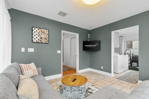Cozy living room with sage green walls, gray sofa, wooden coffee table, and cat artwork.