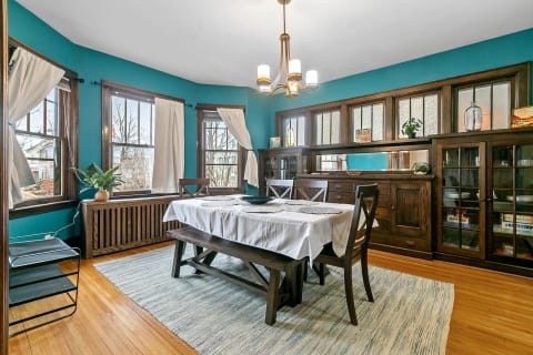 A cozy dining room with turquoise walls, a wooden dining table, and vintage decor touches.