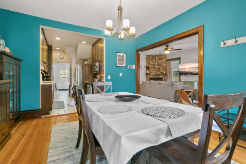 Bright turquoise dining room with wooden table and stylish decor, connecting to kitchen and living area.