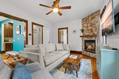 Cozy living room featuring a gray sectional sofa, wooden coffee table, and stone fireplace.