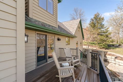 A wooden outdoor deck with rocking chairs and a scenic view of nature.