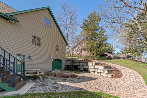 Outdoor view of a tan house with a green roof and an inviting patio area.