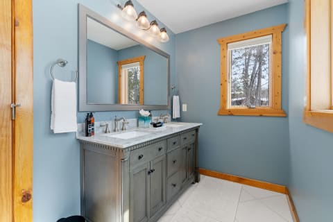 Interior view of a modern bathroom with gray vanity and blue walls.