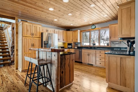 A wooden-themed kitchen with modern appliances, a bar area, and abundant natural light.