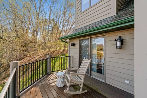 Wooden balcony with a rocking chair and trees in the background during spring.