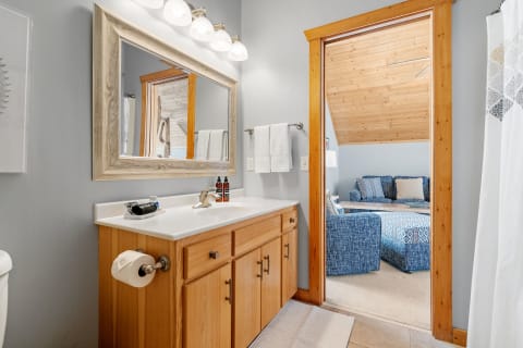 Interior view of a cozy bathroom with wooden cabinets and a doorway to a living space.