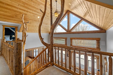 Interior view of a wooden loft with large windows and rustic railing.