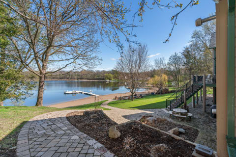 Serene lakeside scene with stone pathway, dock, and green grass.