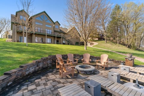 Outdoor seating area with wooden chairs and a fire pit in front of a house.