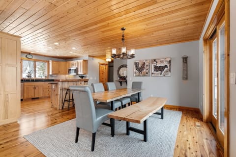 Spacious dining area featuring wooden ceilings, modern kitchen, and rustic decor.