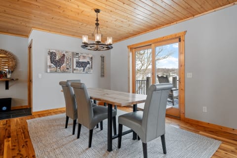 A dining room featuring a wooden table, gray chairs, and decorative farm-themed wall art.