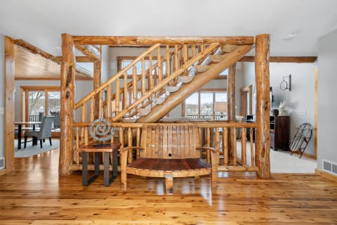 Interior view of a rustic home entryway featuring a wooden staircase and seating.