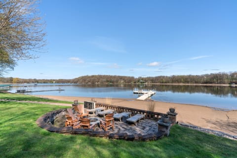 Lakeside patio area with wooden chairs and a dock leading into the water.