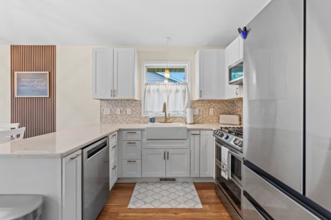 Modern kitchen with gray cabinets, farmhouse sink, and honeycomb backsplash.