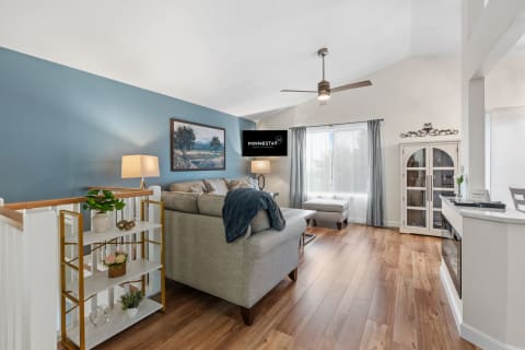 Modern living room with beige sofa, decor, wall-mounted TV, and natural light.