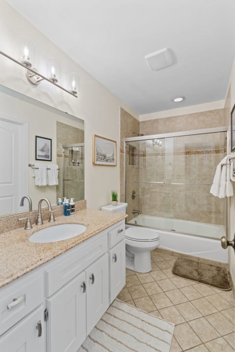 Modern bathroom with a glass shower, granite countertop, and contemporary decor.