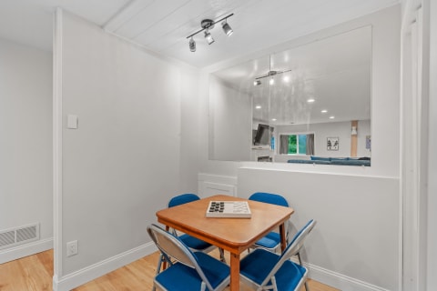 Small dining area with a wooden table, blue chairs, and a checkerboard game.