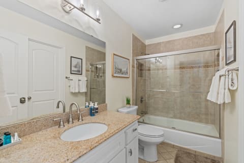 Modern bathroom with granite countertop, glass shower, and clean design.