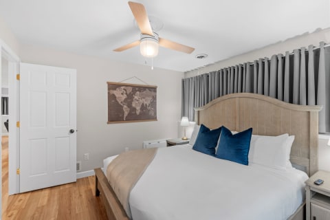 Interior view of a modern bedroom with a bed, blue pillows, and a world map on the wall.
