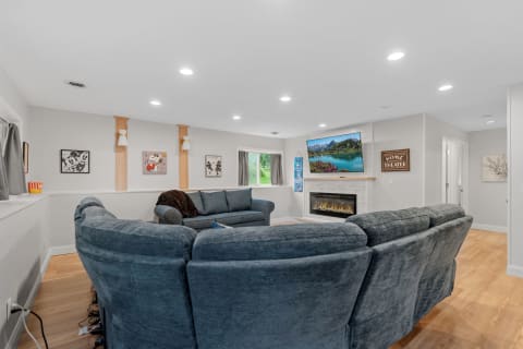 A modern living room featuring a blue sectional sofa, fireplace, and artwork on the walls.