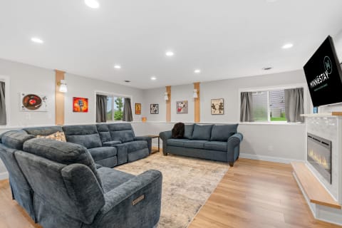 Cozy living room with blue couches, framed art, and an electric fireplace.