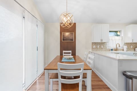 Modern dining area with a wooden table, white chairs, and stylish chandelier.