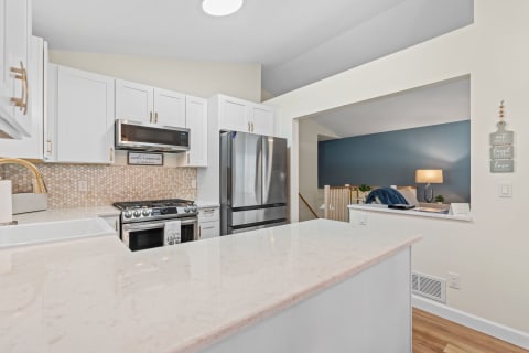 Modern kitchen with white cabinets and a beige hexagonal backsplash.