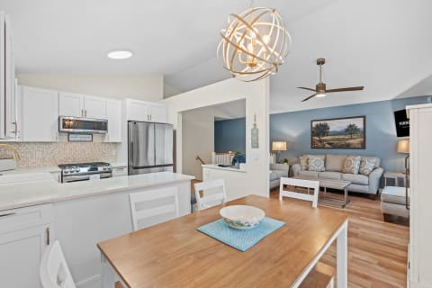 Open kitchen with white cabinets and a cozy living room in the background.