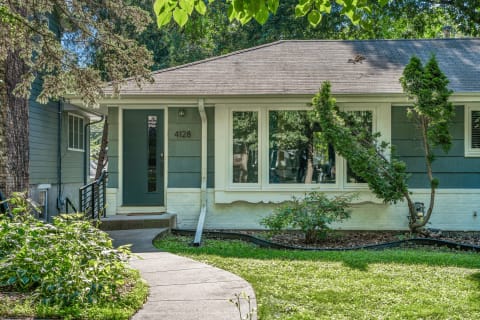 Front view of a cozy single-story house with large windows and landscaped yard.