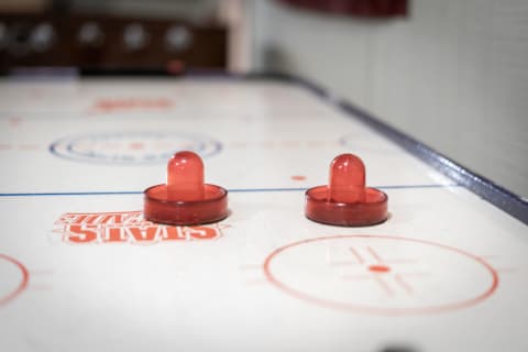 Close-up view of red air hockey strikers on a white game table.