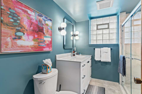 A stylish bathroom with teal walls, a white vanity, and contemporary decor.