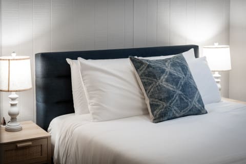 A neatly made bed with blue accents and warm bedside lamps.
