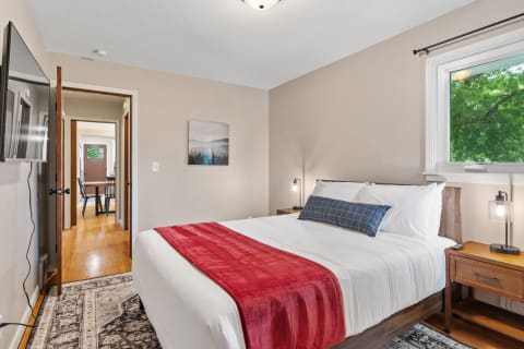 A well-decorated bedroom with a queen bed, nightstands, and artwork.