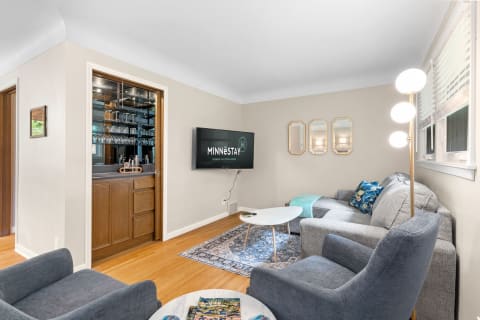 A modern living room with gray furniture, a TV, and a stylish bar area.