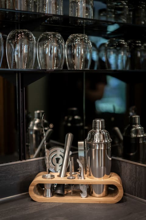 Stylish bar tools displayed on a wooden stand with glassware in the background.