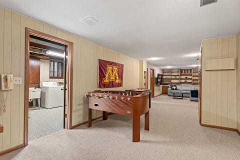 Spacious basement with a foosball table and laundry area in the background.