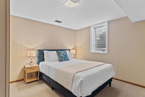 A serene bedroom with a bed, nightstand, and soft lighting.