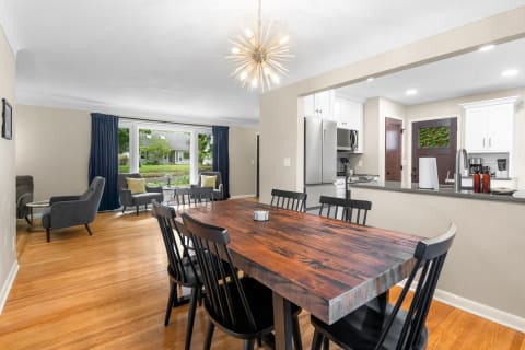 Interior view of a dining area with a wooden table, black chairs, and an open kitchen