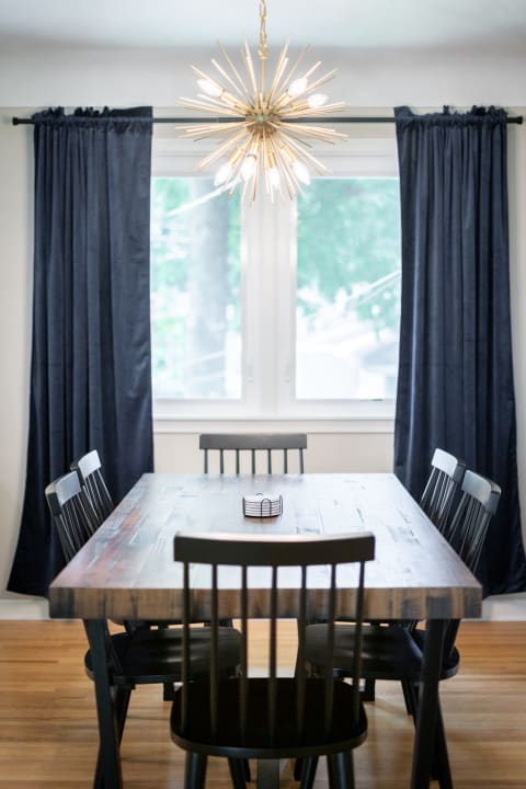 Modern dining room with wooden table, black chairs, and a starburst chandelier.
