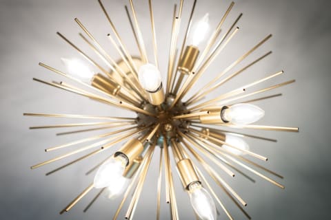 Modern starburst chandelier with gold rods and light bulbs.