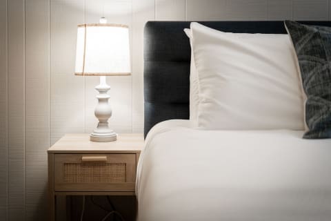 Cozy bedroom corner with a lamp and a neatly made bed.