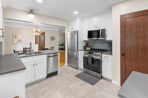 A modern kitchen featuring white cabinets, gray countertops, and stainless steel appliances.