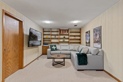 Cozy basement living room featuring a sectional sofa and a flat-screen TV.