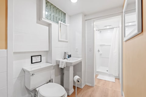A minimalist bathroom with a toilet, sink, shower area, and natural light from glass block windows.