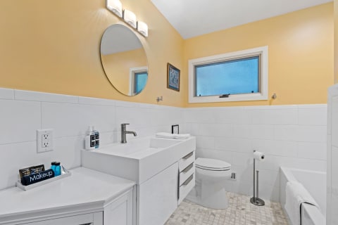 Modern bathroom featuring yellow walls, white tiles, and a minimalist sink.