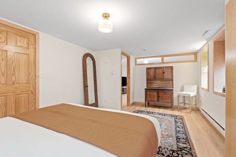 A cozy bedroom with a brown quilted bedspread, wooden furniture, and natural light.
