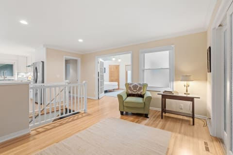 Interior of a home featuring an armchair, wooden table, and kitchen area.