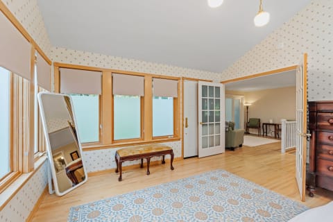 A bright room featuring star-patterned wallpaper, wooden floors, large windows, and an ornate bench.