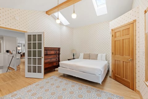 Bright bedroom featuring a bed, wooden dresser, and skylights.